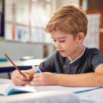 A child writes in a notebook, showcasing concentration and creativity.