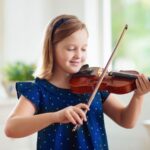 A young girl plays the violin, showcasing her talent and concentration.